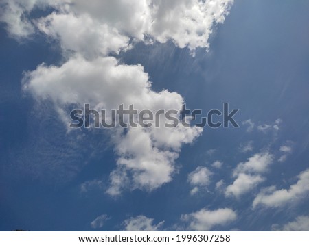 light blue sky with white clouds in the middle of a sunny day