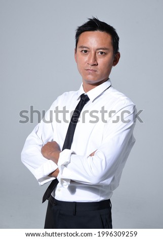 Portrait of young handsome business man in white shirt ,tie with arms crossed on gray background 