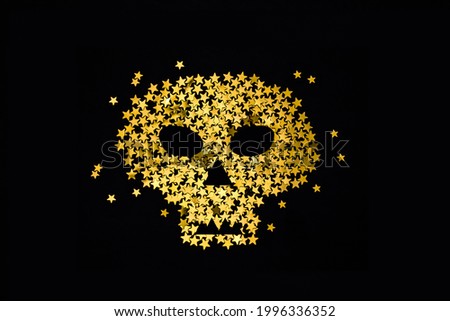 Symbol of gold glitter skull on dark black with sparkles. Halloween party concept.