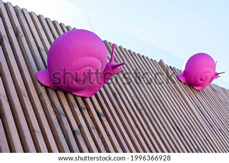 Pink plastic figures of grape snails on a wooden striped background, copy space, design element, abstract modern art