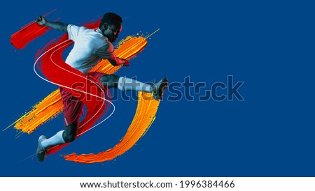 Artwork. Modern design. Young african man, soccer footbal player with ball training in neon light on blue background. Watercolor paints. Concept of sport, game, action. Copyspace for ad. flyer Royalty-Free Stock Photo #1996384466