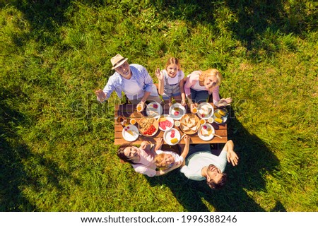 High above angle view family having picnic outdoors cheerful waving hands sunny summer day Royalty-Free Stock Photo #1996388246
