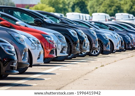 Row of brand new cars lined up outdoors in a parking lot. Royalty-Free Stock Photo #1996415942