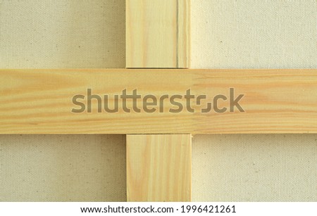 Wooden bars in the shape of a cross lie on a fabric background. 
