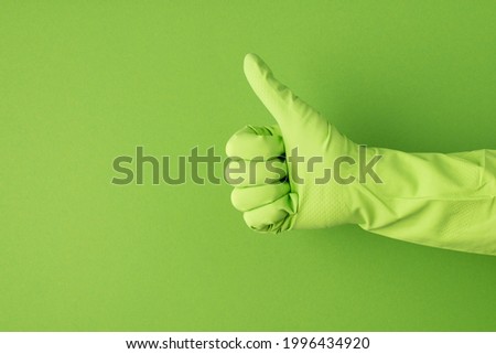 Profile photo of hand in green glove making thumb-up on isolated green background with copyspace