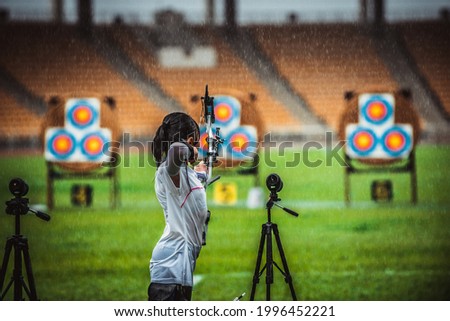 Little girl shoot on Archery Competition in rainy day Royalty-Free Stock Photo #1996452221