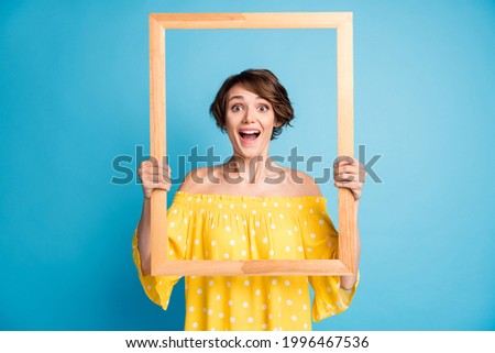 Photo of amazed charming young woman hold frame picture creative shot isolated on pastel blue color background