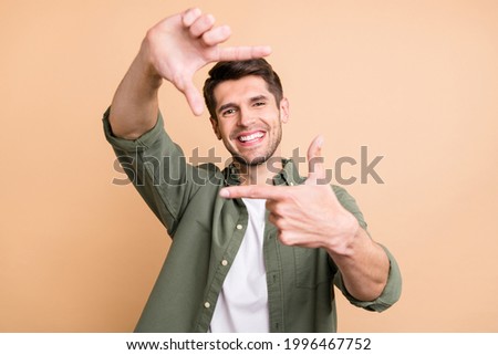 Photo of charming happy young cheerful man make fingers frame smile isolated on beige color background
