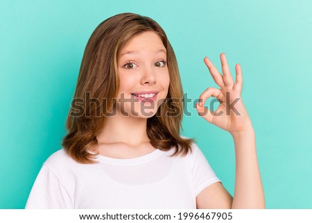 Photo portrait little girl smiling showing okay gesture in white t-shirt isolated bright turquoise color background