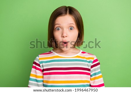 Photo of young little girl amazed shock surprised fake novelty news omg wow reaction isolated over green color background
