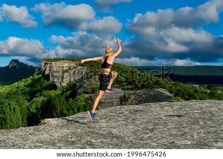 Young woman in sportswear trains in the mountains. The concept of yoga, fitness, meditation, healthy lifestyle, weight loss. Unity with nature.