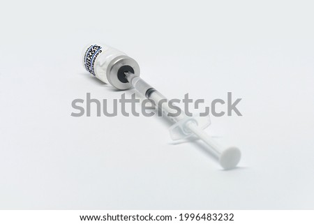 Vial with coronavirus vaccine and syringe on white background, flat lay. Covid-19 - SARS-CoV-2 vaccine