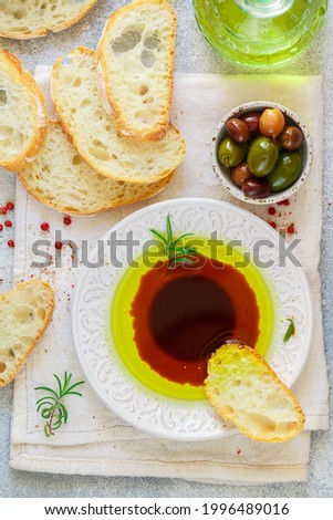 Freshly baked homemade ciabatta and a sauce of olive oil and balsamic vinegar, freshly ground pink pepper, coarse sea salt and rosemary on a light background. Mediterranean cuisine.  top view