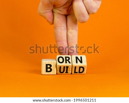 Born or build symbol. Businessman turns wooden cubes and changes the word 'born' to 'build'. Beautiful orange background. Born or build and business concept. Copy space.