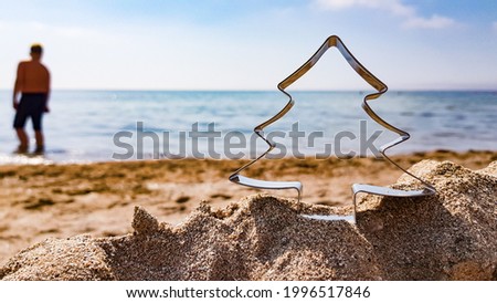 the silhouette of a man on the beach and the outline of a Christmas tree on the sand