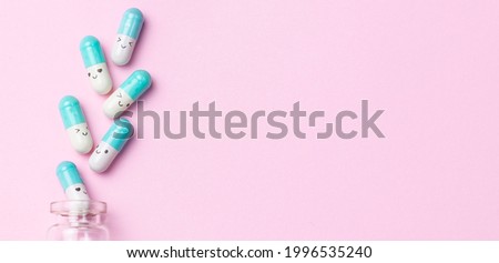 Medical pills with funny faces on light pink background top view. Funny medical banner. Health care concept.
