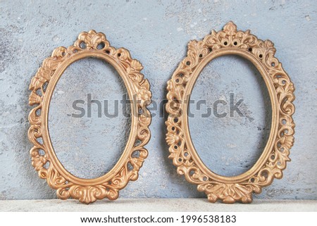Two antique brass empty picture frames on concrete background. Photography props and copy space for text.  