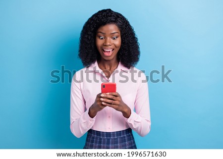Photo portrait of amazed surprised curly brunette reading news with smartphone isolated on bright blue color background