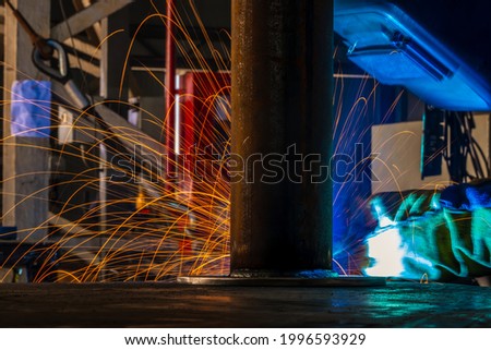 A welder performs semi-automatic arc welding at a manufacturing facility.