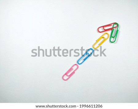 Selective focus.Colorful paper clips are arranged like arrows on a white background.