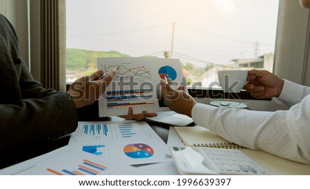 Businesswomen and men reading financial reports, discussing, analyzing, calculating graph documents that Asian female and male managers discuss and scrutinizing negotiation decisions. work as a team a