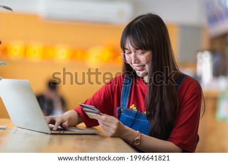 Smile and happy a asian woman using credit card in hand with laptop computer on wooden table for shopping, business concept.