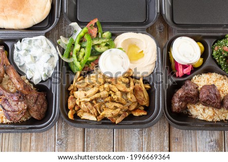 A top down view of a three Mediterranean combos in to-go containers, featuring lamb rack, chicken shawarma and beef kabob.