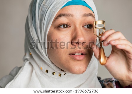 Young Islamic woman curling her eyelashes Royalty-Free Stock Photo #1996672736