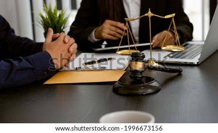 Lawyer discussing contract documents sitting at a desk at the office Legal concepts, advice, legal advisory services and scales with a judge's hammer put forward. Royalty-Free Stock Photo #1996673156