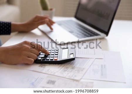 Crop close up of Indian woman manage household expenses expenditures calculate on machine pay on computer online. Ethnic female make web payment consider budget finances at home. Banking concept. Royalty-Free Stock Photo #1996708859
