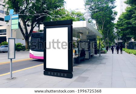 Blank advertising poster banner mockup at bus stop shelter by main road; out-of-home OOH vertical billboard media display space. Perspective angle Royalty-Free Stock Photo #1996725368