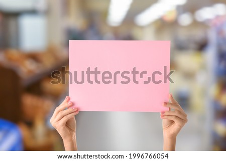 Female hands with blank poster in grocery market