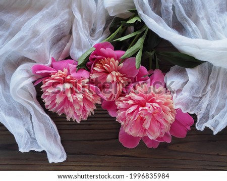 Delicate bouquet with pink peony flowers on a wooden table with a white handkerchief. Spring romantic picture with flowers for invitation design, greeting card, wallpaper