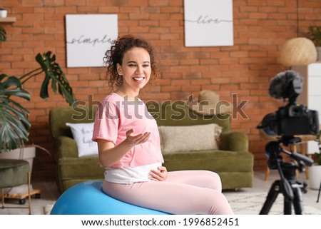 Young pregnant blogger recording sports video at home