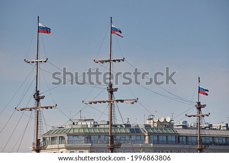 Wooden masts of a sailboat with flags of Russia against the blue sky