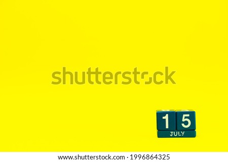 Date 15 July on blue wooden cubes on a bright yellow background with place for text