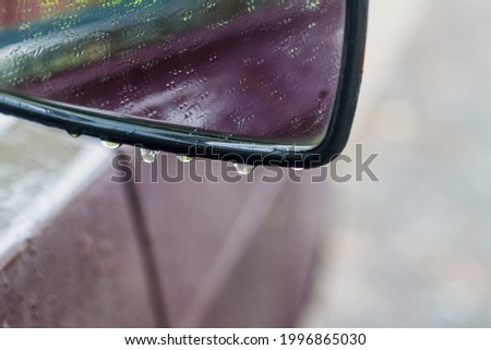 Car side mirror in the rain in water drops.