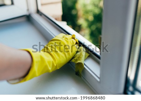 A person wearing gloves washes the window frame with a cleaning cloth. Royalty-Free Stock Photo #1996868480