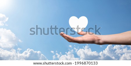 Male hand holding heart , like icon on blue background. Kindness, charity, pure love and compassion concept.Banner with copy space.
