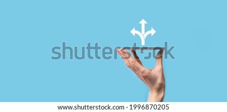 Male hand holding icon with three directions icon on blue background.n doubt, having to choose between three different choices indicated by arrows pointing in opposite direction concept. three ways 