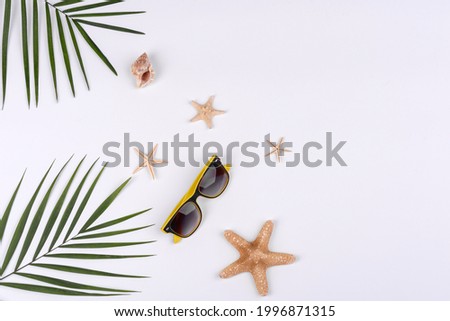 Beach accessories: glasses and hat with shells and sea stars on a white background. Summer background
