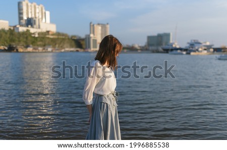 Woman in dress enjoys the sea shore.