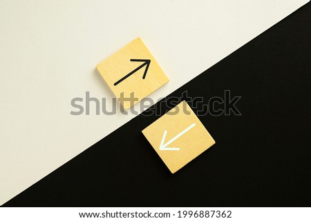 Black and white  the opposite direction arrows on wooden cube over black and white paper that is split in half background use for opposites direction concept.