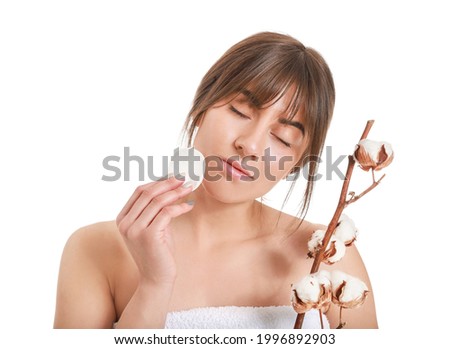 Beautiful young woman with cotton flowers and cosmetic pad on white background