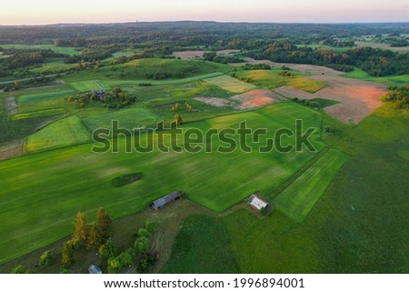A beautiful view of forests and green fields from above with a sun on golden hour. Drone photography of Europe agricultural region.
