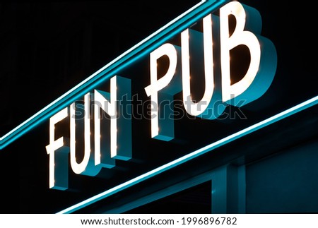 Bright modern sign of fun pub glowing on background of night sky in city