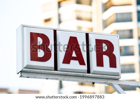 Low angle of metal shabby signboard of bar located on city street at daytime