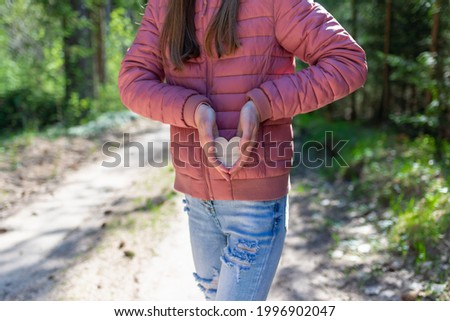 One joyful teen girl in forest holding a wooden heart in her hands.On spring or summer nice sunny day.Selective focus.