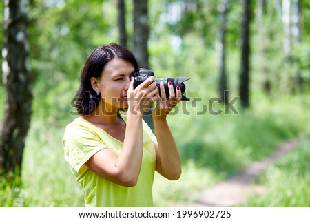Portrait of a woman photographer covering her face with the camera outdoor take photo, World photographer day, Young woman with a camera in hand.