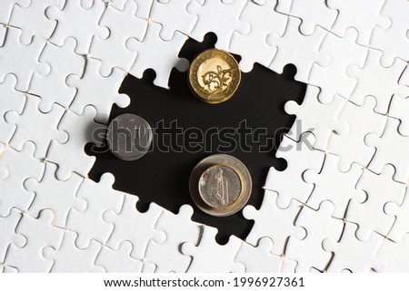 golden coins with incomplete white jigsaw puzzle and black background